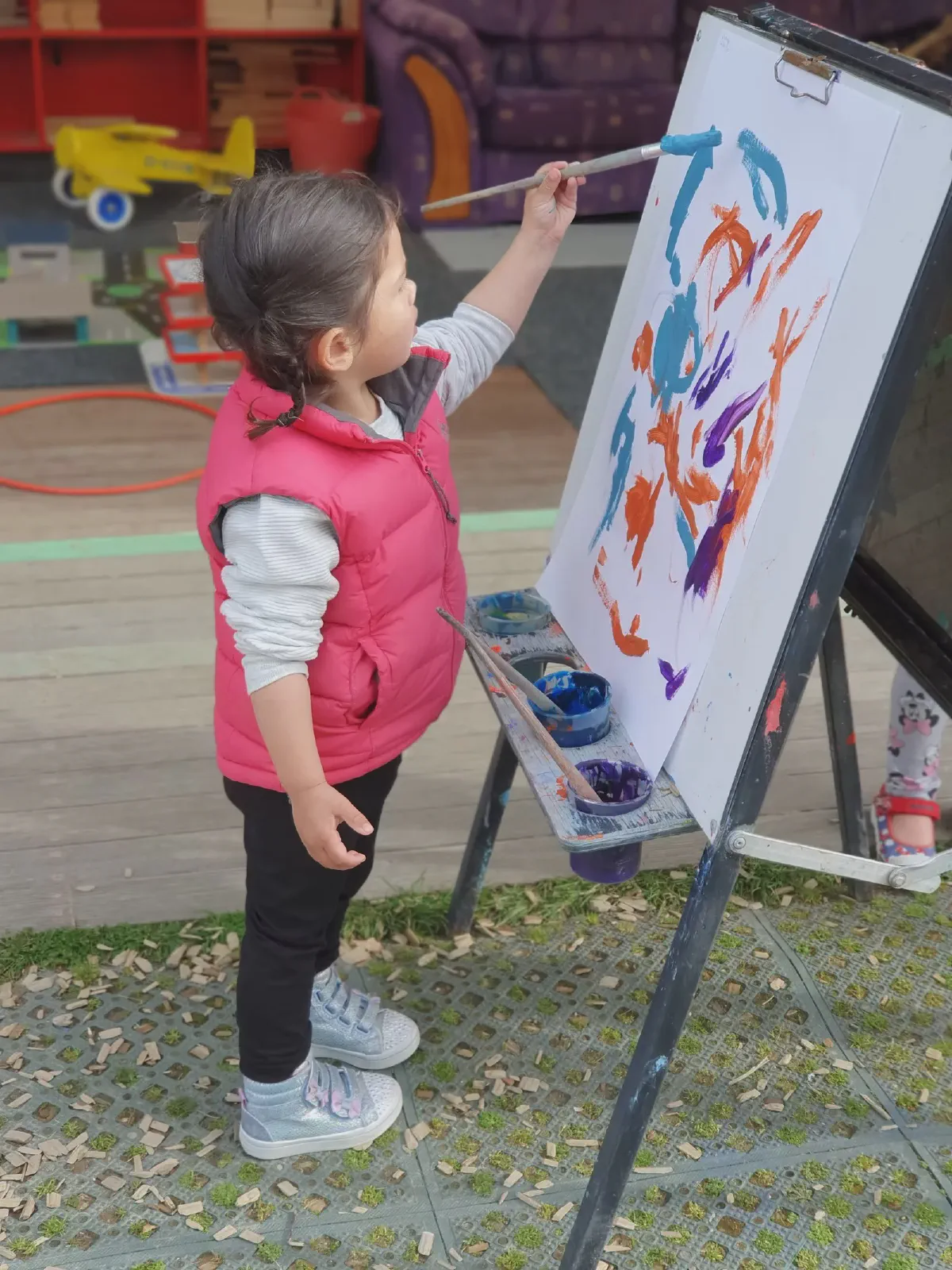 A child painting at an easel outdoors